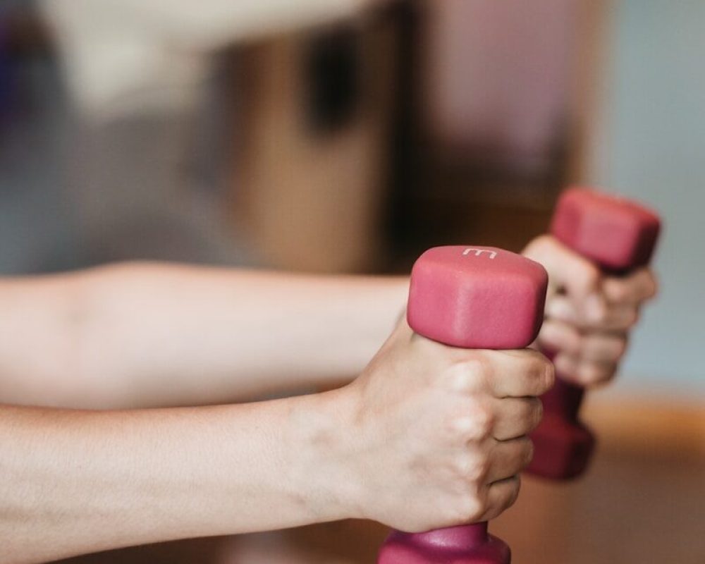 person holding pink and white dumbbells